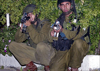 Israeli soldiers take cover during a search for wanted Palestinian militant activists near the al Berh Mosque in the West Bank city of Ramallah late September 30, 2003. In Israeli military raids, troops seized several suspected militants near the West Bank cities of Nablus, Ramallah and Hebron, the army said. REUTERS/Ammar Awad