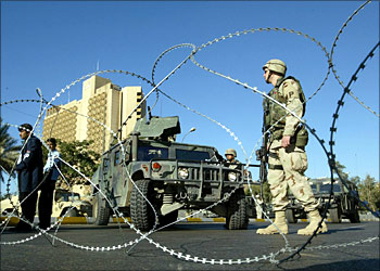 US soldiers andU members of Iraqi police (L) secure the perimeter of the Palestine (background) and the Sheraton hotels early 21 November 2003 in Baghdad. Two people were wounded in the attack where main medias and international companies are based
