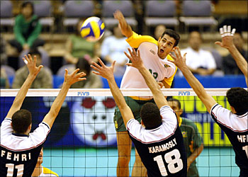 Brazilian attacker Dante Amaral (C, rear) spikes the ball over Tunisian defenders, Marouan Fehri (L, 11#), Hosni Karamosly (C, front, 18#), Noureddine Hfaiedh (R), during the World Cup men's volleyball tournament at the Hamamatsu Arena, Shizuoka Prefecture, 21 November 2003.Brazil made it five wins when they swept to an expected straight-sets victory over Tunisia with a 3-0 (25-17, 25-16, 25-11
