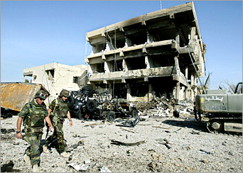 Two Italian soldiers walk in front of the destroyed building November 13, 2003, which once housed the Italian military police in the southern Iraqi city of Nassiriya. While visiting the site, Italian defence minister Antonio Martino denied ther had been a lack of security at the military police base in Nassiriya where Wednesday's suicide attack killed 27 people, including 18 Italians. REUTERS/Zohra Bensemra