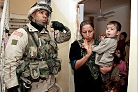 A US soldier from 2nd Battalion, 325th Airborne Infantry regiment orders an Iraqi woman and her kids to leave the room as they raid her house 06 December 2003 southeast of Baghdad. US troops acting on a tip about one of the wives of Saddam Hussein's fugitive number two Izzat Ibrahim detained the brother of a security guard from Ibrahim's office. Soldiers raided the house after receiving a tip during a large search for weapons and Saddam loyalists. They found three women and eight young children at the house. The women denied knowing Ibrahim and was not detained. AFP PHOTO/Henghameh FAHIMI