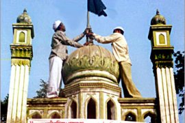 Two Indian Muslim men adjust a black flag on the top of a mosque in Ayodhya, 06 December 2003, on the 11th anniversary of the demolition by Hindu radicals of the Babri Mosque in the northern Indian town. Muslims across India gathered in protests to demand that those responsible for the 1992 destruction of the16th-century Babri Mosque in Ayodhya be brought to justice and that the mosque be reconstructed on its original site. AFP PHOTO
