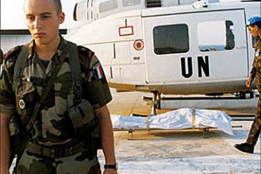 F_A French (L) and Indian UN peacekeepers from UNIFIL stand close to a covered body 10 December 2003