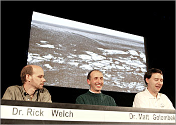 Dr. Matt Golombek (C), science team member, smiles as he presents the lastest images returned from the martian surface by the Mars Exploration Rover (MER) Opportunity 28 January 2004 at a press conference at NASA's Jet Propulsion Laboratory (JPL) in Pasadena, California. This image, a detail of a panorama image captured by the Opportunitys panoramic camera, highlights the flat and dark terrain of its landing site at Meridiani Planum. At left is Dr Rick Welch, Activity Lead; at right is Dr Jim Bell (C), Lead Scientist for the Pan Cam. AFP PHOTO / Robyn BECK