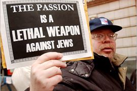 A protester displays a sign handed out to about three dozen Jewish demonstrators gathered in front of a Times Square movie theater to protest the depiction of Jews in the Mel Gibson film The Passion of the Christ, in New York on February 24, 2004, a movie which they have not seen. The movie, which opens tomorrow, has drawn both praise and criticism from religious groups. REUTERS/Chip East