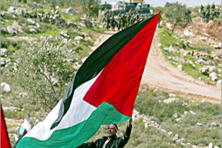 A Palestinian waves a Palestinian flag during a demonstration in the West Bank village of Budrus 23 February 2004 against the Israelis security barrier which passes over their land. The International Court of Justice (ICJ) in The Hague began hearings into the legality of the separation barrier being built by Israel along the West Bank. AFP PHOTO/Jamal ARURI