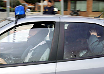 One of the five suspects in connection with the railway bombings that struck Madrid one week ago (hidden) and flanked by a policemoman leave the General direction of the police, the so-called Canillas district on his way to the National audience, Spains high court, 18 March 2004 in Madrid. All of the suspects are due to appear before Judge Juan del Olmo who must decide whether to charge or free them. AFP PHOTO PEDRO ARMESTRE