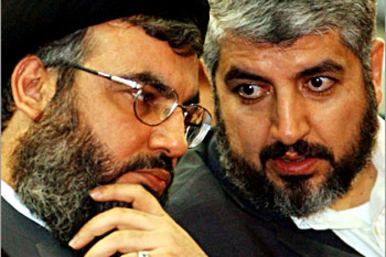Lebanons Hizbollah leader Sheikh Hassan Nasrallah (L) talks to Lebanons Palestinian Hamas leader Khaled Meshaal (R) during a rally in Beirut March 27, 2004. Nasrallah told thousands of suppoters gathered at a memorial service for assassinated Hamas spiritual leader Sheikh Ahmed Yassin, that Hamas could consider Hizbollah under its command. REUTERS/Mohamed Azakir