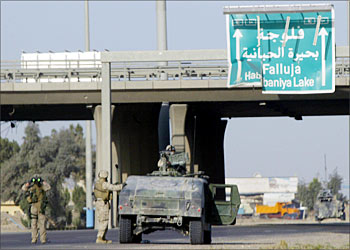 F_US soldiers block the main entrance to the restive town of Fallujah, 50 kms west of Baghdad, 26 March 2004. A US Humvee was burnt 25 March after it came under attack during a shootout in Fallujah, in which one US marine was killed and two others were wounded. AFP PHOTO/Nicolas ASFOURI