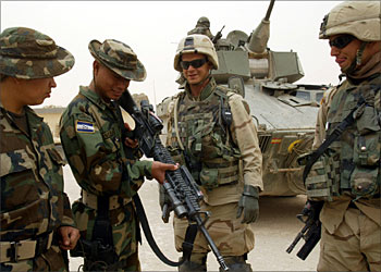 F_U.S.soldiers from 2nd Battalion, 2nd Regiment of the First Infantry Division show their weapons to their Honduran colleagues at a coalition forces base near the Iraqi holy city of Najaf on April 17,2004. REUTERS/Laszlo Balogh