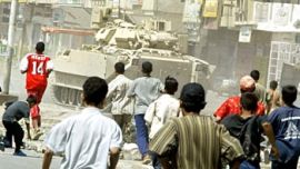 f:  Iraqi children run after a US tank to hurl stones at it 15 May 2004 in Baghdad's Shiite neighborhood of Sadr City.