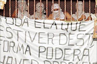 r / Inmates at Rio de Janeiro's Benfica prison hold up a message for authorities, during a riot, May 31, 2004. The message reads, "All