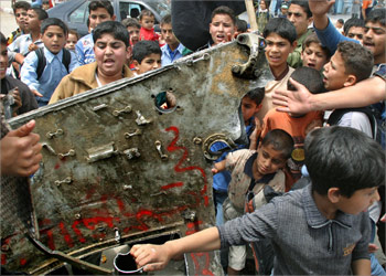 Palestinian carry a piece of an Israeli military vehicle after it was blown up in Gaza, May 11, 2004. Palestinian militants blew up an Israeli military vehicle in the Gaza Strip on Tuesday, killing six soldiers during a raid in which troops shot dead four Palestinians, witnesses said. REUTERS/Mohammed Salem