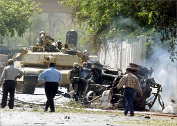 US troops, Iraqi policemen and civilians survey the site where a car bomb exploded 17 May 2004 at a checkpoint at the entrance of the Coalition Provisional Authority (CPA) headquarters in Baghdad