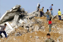 Palestinians walk amid the rubble of a destroyed house in Deir al-Balah in the Gaza Strip 27 May 2004. Since August 2002, the Israeli army has destroyed hundreds of family homes in the West Bank and the Gaza Strip belonging to Palestinians accused of involvement in anti-Israeli attacks, sparking accusations from human rights watchdogs of collective punishment. The Israeli army has also carried out a mass program of demolition in Rafah in the southern Gaza Strip, the scene of a week-long raid that ended 24 May, claiming the lives of more than 40 Palestinians. AFP PHOTO/MOHAMMED ABED