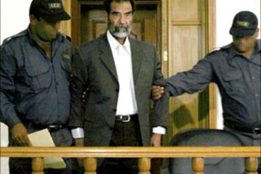 F/A picture released 02 July 2004 by the US Department of Defense shows former Iraqi president Saddam Hussein being led by guards into the courtroom for his initial interview with an Iraqi judge at an undisclosed location in Baghdad 01 July 2004