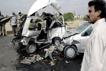 f/Pakistani security personnel inspects the wreckage of two cars which were destroyed after a bomb exploded on a road in the outskirts of Karachi, 24 July 2004