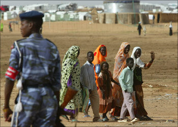 r - Sudanese displaced people walk in front of a Sudanese soldier at Abushock camp in northern Darfur region of Sudan, August 16, 2004. The United Nations says up to 50,000 people have been killed and a million displaced since fighting broke out in Darfur between the Sudan government and two rebel groups in early 2003, sparking what has been called the world's worst humanitarian disaster. REUTERS/Antony Njuguna