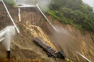 AFP - A large truck lies on the sloap after the landslide swept the road
