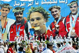 Fans gather under a banner depicting the pictures of Egyptian Olympic medalists (L to R) Tamer Bayoumi, Taekwondo men's 58kg Bronze medal, Mohamed Elsayed, boxing heavyweight