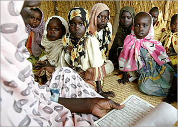 A Sudanese teacher reads to children at an Islamic school in the Abushock camp for displaced people in northern Darfur region of Sudan, August 16, 2004. The United Nations says 50,000 people have been killed and a million displaced since fighting broke out in Darfur between the Sudan government and two rebel groups in early 2003, sparking what has been called the world's worst humanitarian disaster. REUTERS/Antony Njuguna