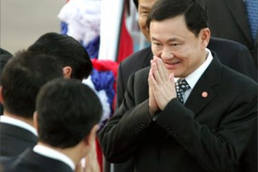 Thailand's Prime Minister Thaksin Shinawatra greets staff upon his arrival at Vientiane's Wattay international airport on the eve of the 10th Association of Southeast Asian Nations (ASEAN) Summit in Laos, on November 28, 2004