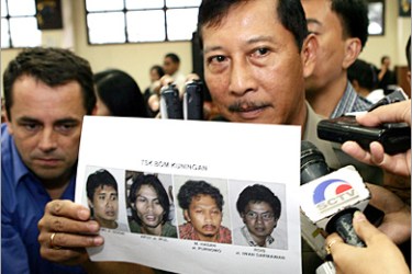 REUTERS - An Indonesian senior police official Suyitno Landung (C) holds pictures of four key suspects (L-R) Ansori, Apuy,