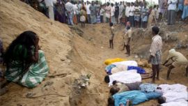 A woman (L) cries as other people watch the burial of victims, mainly children, killed in a tsunami on Sunday in Cuddalore, 180 km (112 miles) south of the southern Indian city of Madras December 27, 2004