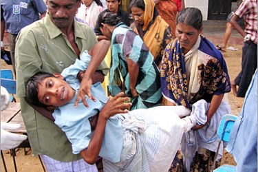 AFP - An injured child is carried to received medical attention at a refugee camp in Ampara, 02 January 2005. Floods slowed