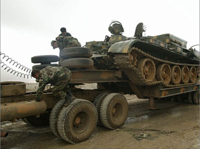 f_Syrian army soldiers load their tank onto a truck as they evacuate