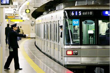 REUTERS/ A Tokyo subway worker gestures as a car at Tsukiji subway station of Tokyo Metro Hibiya Line moves off in Tokyo March 20, 2005. Subway workers observed a moment of silence at 8