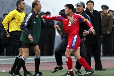 North Korean captain Ri Myong Sam (R) goes after the referee after the later sent off the former's teammate Nam Song Chol in their Group B Asian zone World Cup soccer qualifier against Iran at the Kim Il-Sung stadium in the North Korean capital of Pyongyang, 30 March 2005. Fans threw bottles onto the pitch after disputing refereeing decisions in which North Korean lost 2-0.