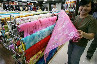 f_A woman rolls up material at a textile market in Beijing, 26 April 2005