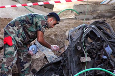 r_A Lebanese soldier inspects a damaged car at a bomb site in the port-city of