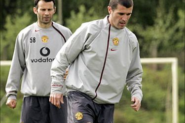 Manchester United captain Roy Keane (R) is watched by Ryan Giggs (L) as he controls the ball during training at Carrington May 18, 2005. Manchester United are due to face Arsenal in the FA Cup final on Saturday May 21, 2005. REUTERS/Ian Hodgson