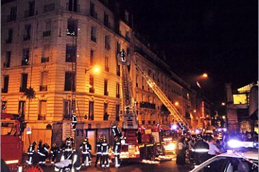AFP - Firemen evacuate victims after a blaze ripped through a dilapidated apartment building in Paris, 26 August 2005. About 210 firemen from 23 stations were mobilized to fight