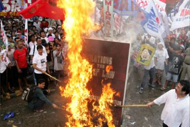 Filipino protesters burn a mock legal book during a protest outside the House of Representatives where lawmakers continue the impeachment hearing against President Gloria Macapagal Arroyo at Quezon City