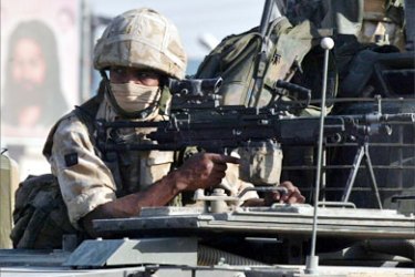 A British soldier keeps watch from atop an armoured vehicle during a patrol in the southern Iraq city of Basra September 25, 2005. An Iraqi judge has issued arrest warrants for two British soldiers accused of killing a policeman in Basra,