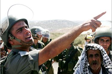 REUTERS/ An Israeli soldier stops the way of an elderly Palestinian man during a protest against the controversial Israeli barrier in the West Bank village of Bilin, September 16, 2005. Foreign