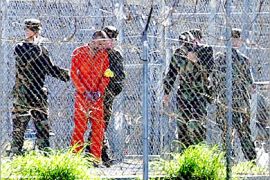 AFP (FILES) A prisoner (2nd L) wearing an orange jump suit can be seen at Camp X-Ray surrounded by heavy security at the Guantanamo Naval Base, US, 17 January,