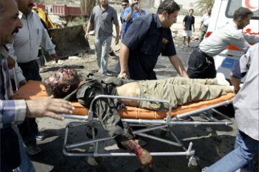 Iraqi men evacuate a body at the site of a suicide attack in Baghdad 25 September 2005. Nine people were killed, five of them police commandos, when a suicide bomber drove an explosives-ladden car into a police convoy in southeastern Baghdad, an interior ministry official said. Twelve people, most of them civilians, were also hurt in the blast.