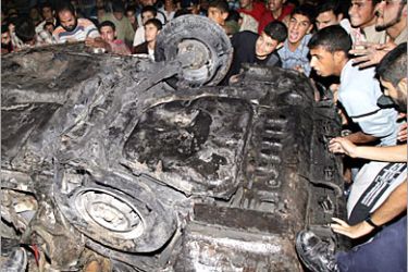 AFP/ Palestinian civilians gather around the wreckage of a car following an Israeli air strike in the Jabalya Refugee camp in the northern Gaza Strip, 27 October 2005. At least seven