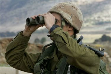 r - An Israeli soldier looks through a pair of binoculars over Lebanon at the Ghajar village on Lebanese border November 22, 2005