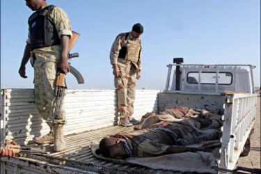 r - Iraqi soldiers load the dead bodies of those killed in a clash with insurgents