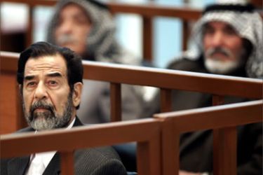 Former Iraqi President Saddam Hussein listens to a member of the prosecution during his trial held under tight security in Baghdad's heavily fortified Green Zone, 05 December, 2005