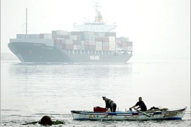 AFP - A cargo ship sails through the Suez canal towards the Timsah Lake as fishermen go about their business in Ismalia, Egypt, 14 December 2005. Egypt will increase