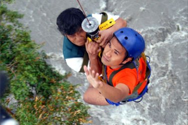 A rescuer (R) helps a man trapped in flood waters into a helicopter at Calapan, 18 December 2005. Widespread flooding in the central Philippines has brought the death toll to six with nearly 13,000 other residents displaced, rescuers said 19 December