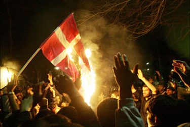 f_Iranian demonstrators burn a Danish flag in front the Danish embassy in Tehran 06 February 2006. Protests
