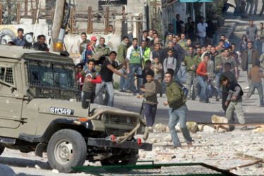 Palestinian youth throw stones at Isreali soldiers during an army operation in the West Bank town of Jenin, 16 March 2006.