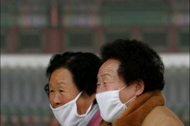 r - South Koreans wear masks to protect themselves from yellow dust in Seoul March 13, 2006. South Korea received a rare snow fall mixed with yellow dust on Monday